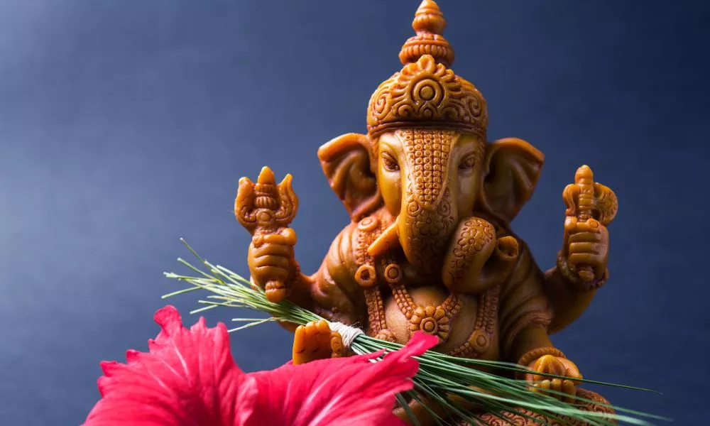 Happy Ganesh Chaturthi Greeting Card showing photograph of lord ganesha idol, pooja or puja thali, bundi laddu/modak, durva and hibiscus or jasvand flower