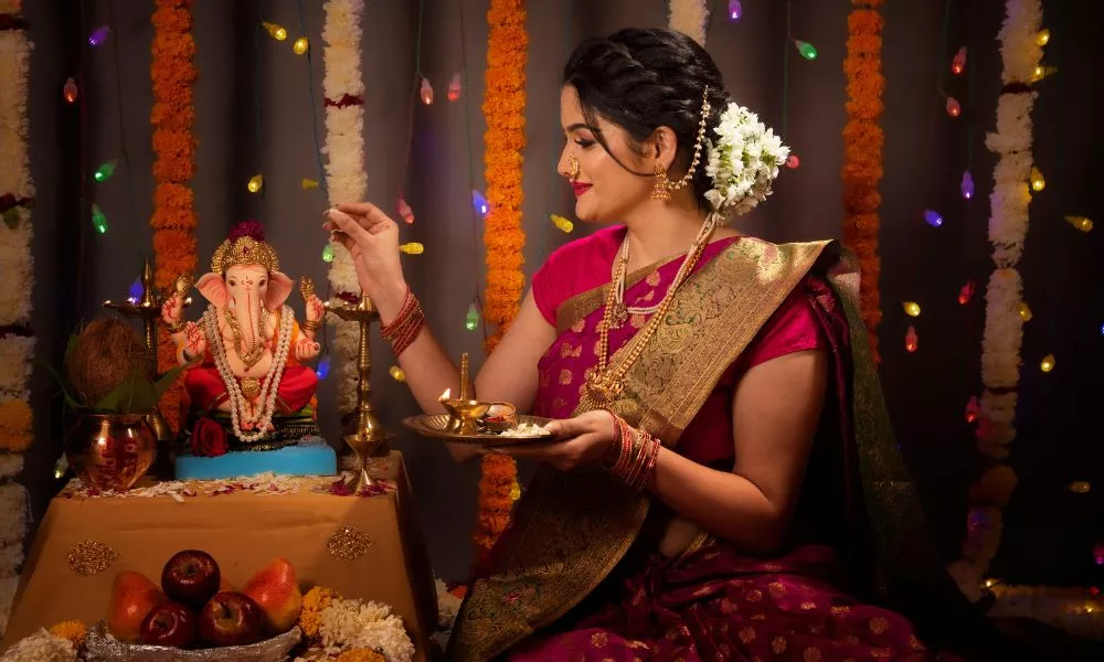Young Indian woman performing rituals of Ganesh pooja during Ganesh Festival