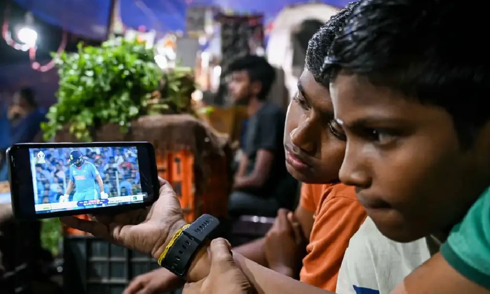 A couple of young fans watch the India-Pakistan game at a market in New Delhi