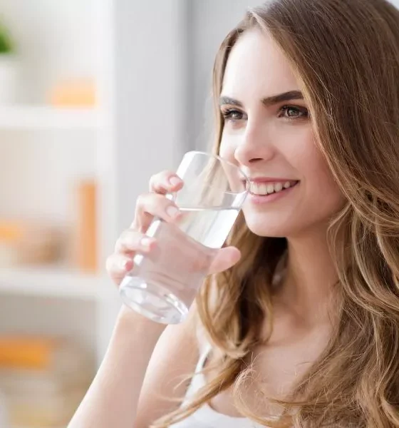 Positive woman drinking water