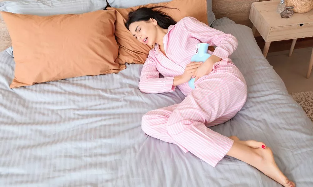 Young Woman Suffering from Menstrual Cramps in Bedroom