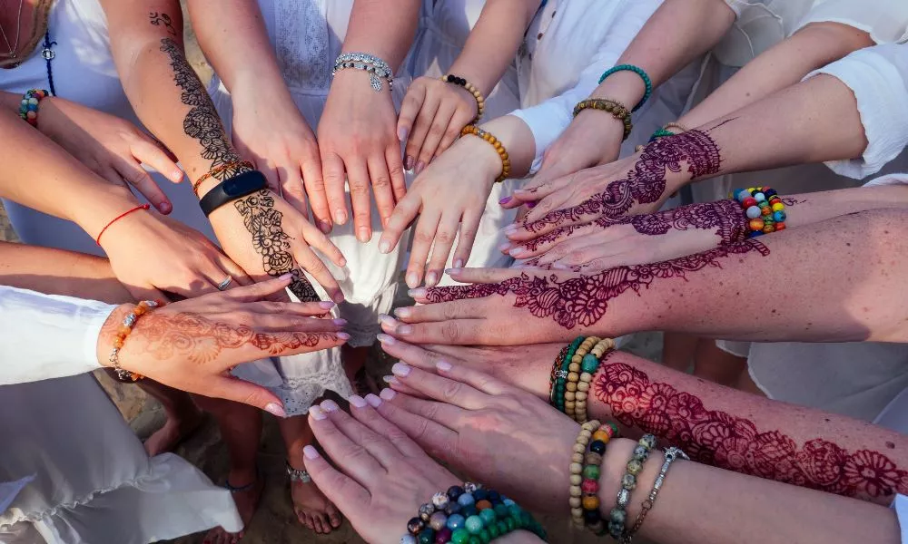 females hands with mehendi art and bracelets at surcle teamwork