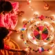 Women Sitting on the Floor Holding Candles Beside Colorful Flowers During Diwali Festival