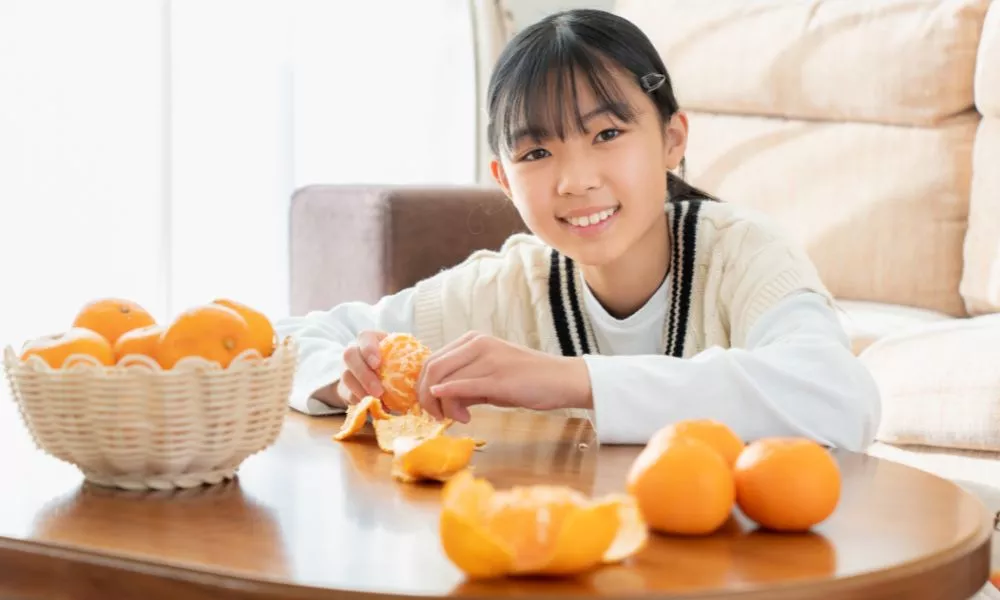 Asian woman eating oranges on the kotatsu in the living room
