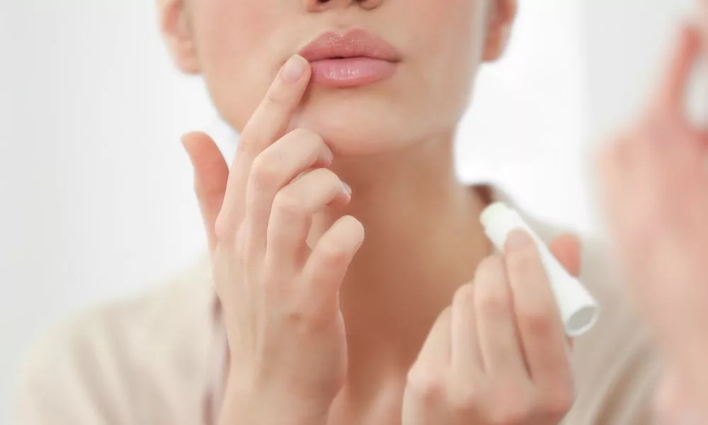 Woman Applying Hygienic Lip Balm near Mirror