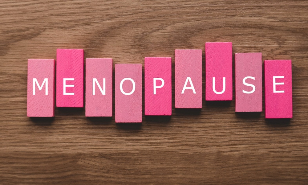 Word Menopause Written on White Background, View through Hole in Pink Paper