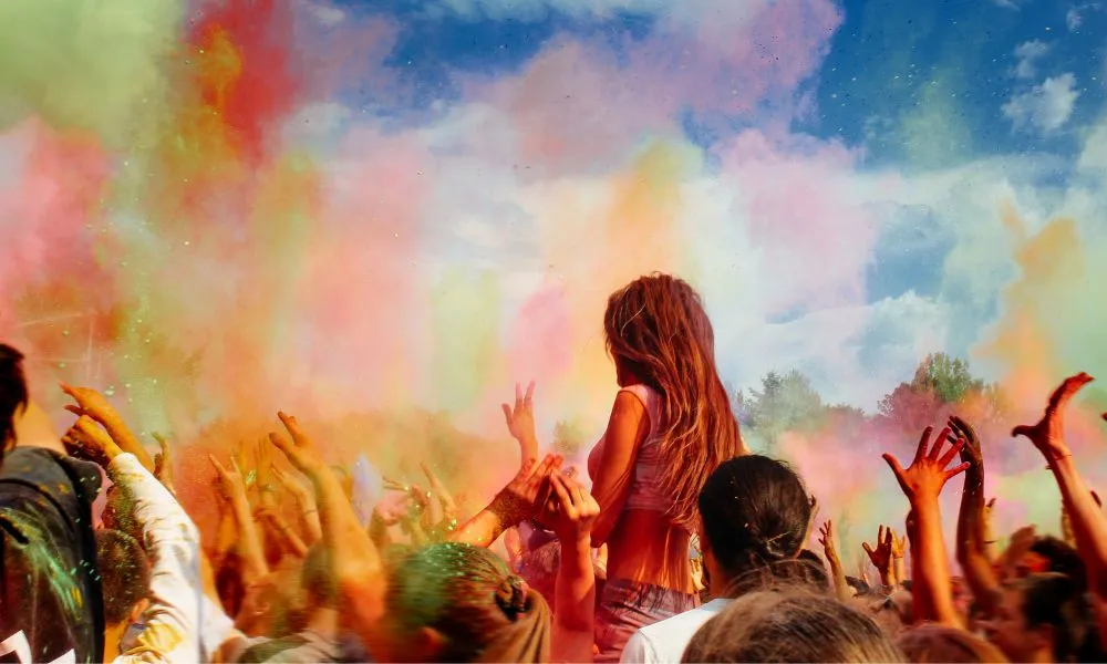 Happy People Crowd Partying under Colorful Powder Cloud at Holi