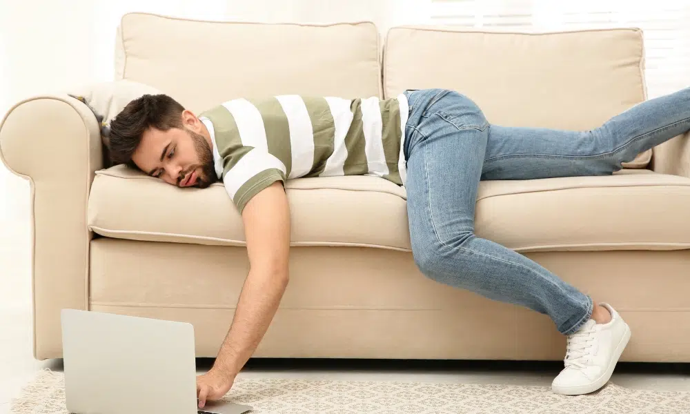 Lazy Young Man Using Laptop While Lying on Sofa at Home