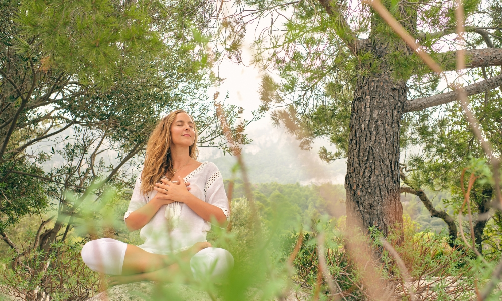 Woman meditating with hands on chest in forest