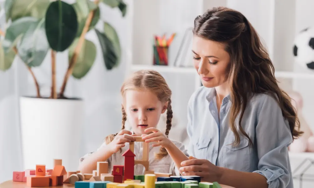 psychologist playing blocks with little child with autism syndrome