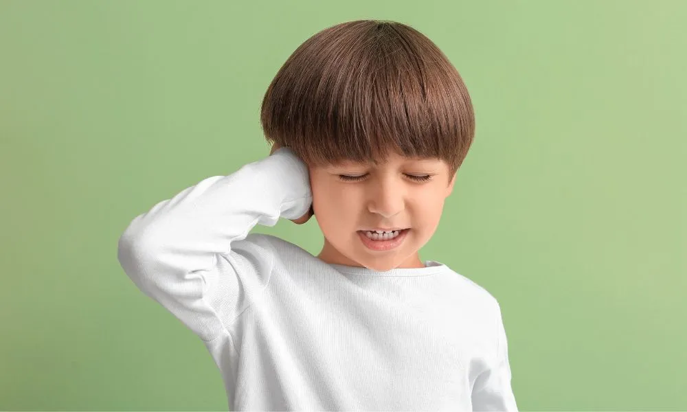 Little Boy Suffering from Ear Pain on Color Green Background
