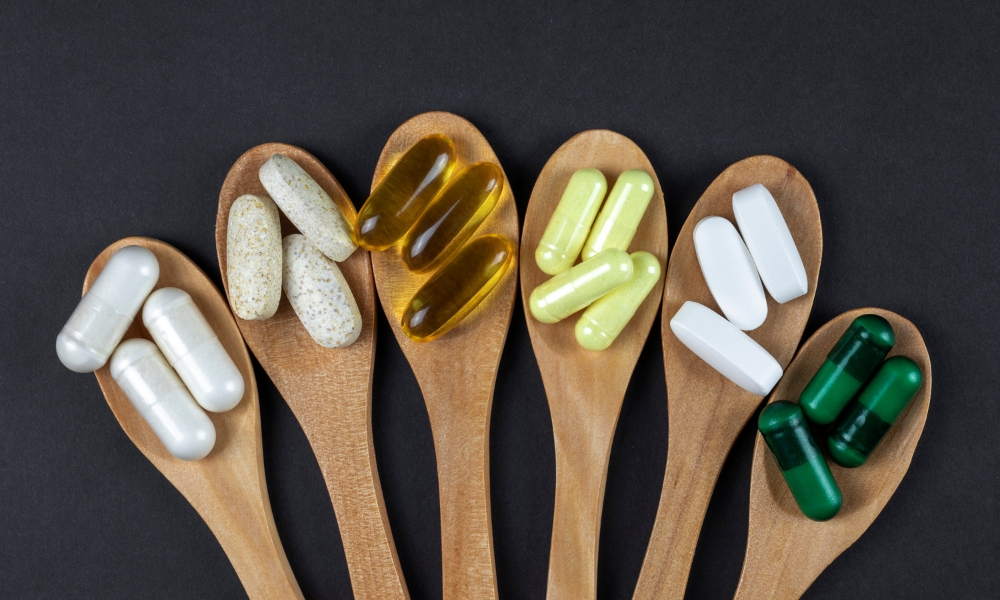 Healthy vitamins and supplements on wooden teaspoons against
