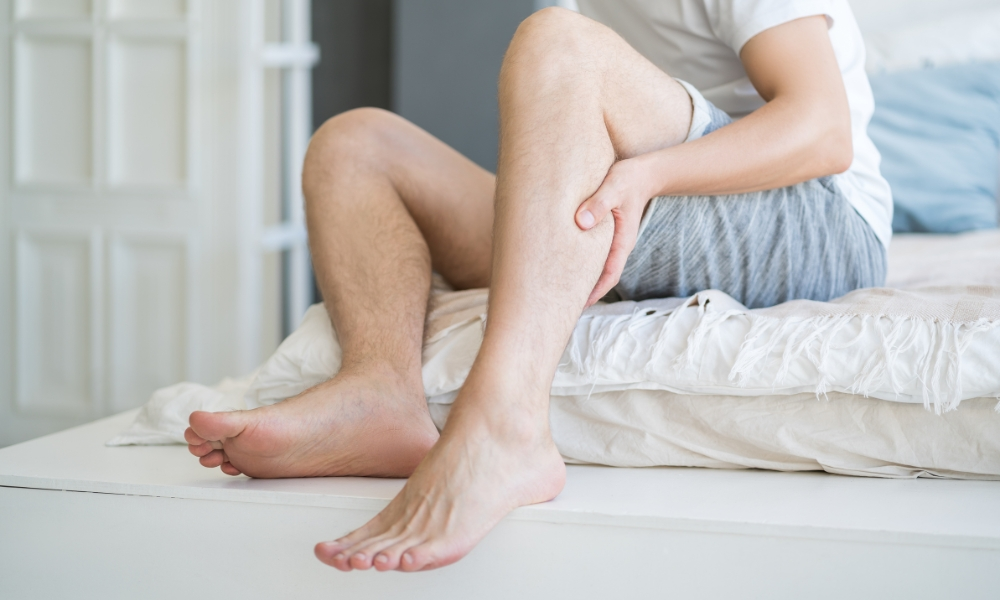 The man's calf muscle cramped, massage of male leg at home