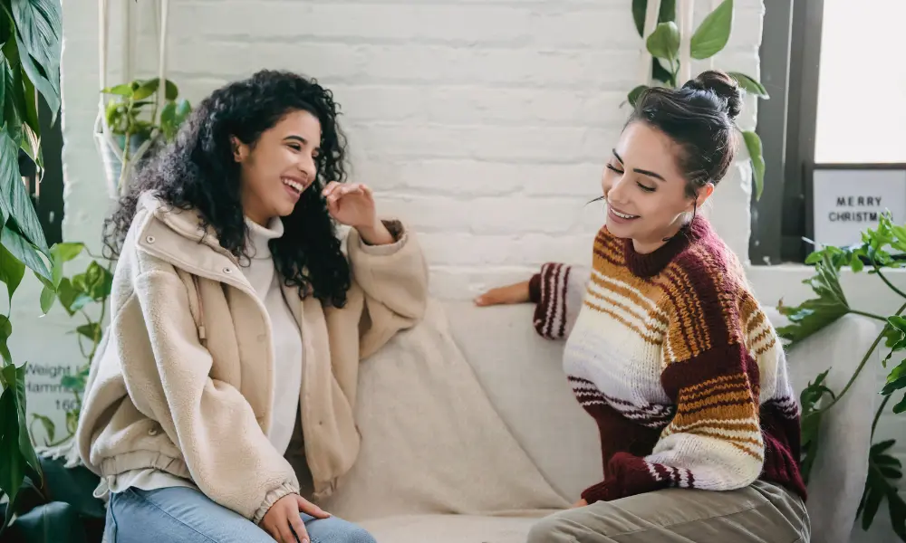Happy young women sitting on couch and talking